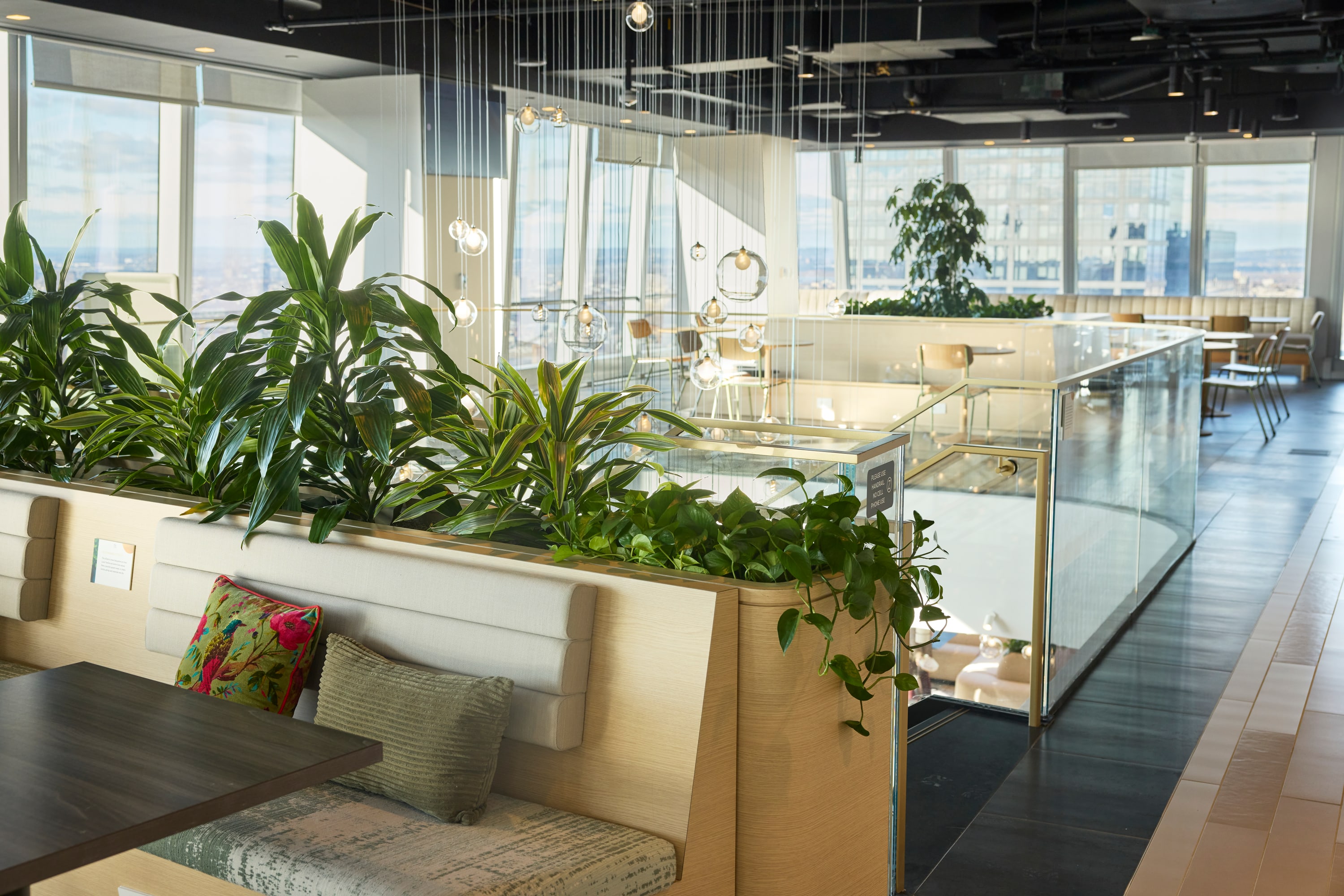 Custom millwork planters built into communal banquette seating at a Manhattan beauty brand headquarters, by Greenery NYC