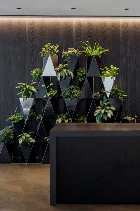 A stylish custom planter adorned with lush green plants, creating a striking contrast and adding a touch of nature to the space.