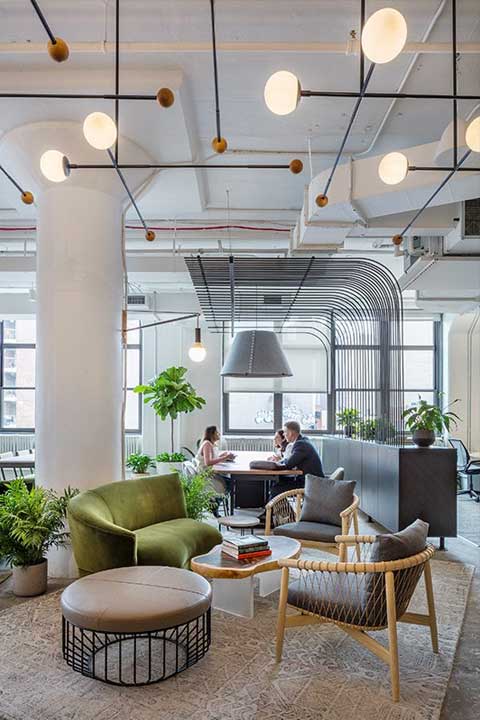 Office space showcasing a big table and chairs in a roomy, open area filled with plants, perfect for productive work and gatherings.